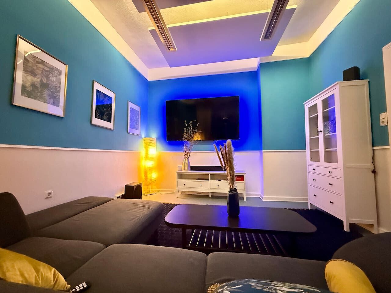 Ein modernes Wohnzimmer mit Flachbildfernseher, einer Couch, einem Couchtisch und einem Schrank.