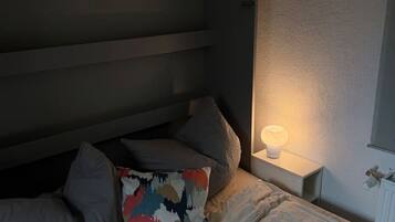Ein Bett mit Kissen, eine Nachttischlampe und ein Heizkörper an der Wand.