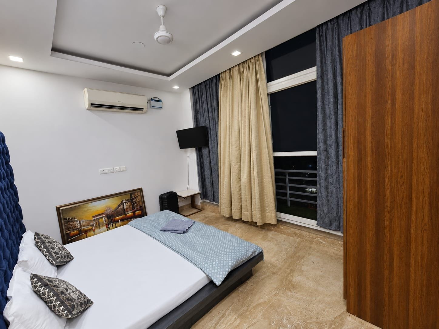 Habitació d'hotel moderna amb llit, televisió de pantalla plana, aire condicionat, finestra amb cortines i balcó.