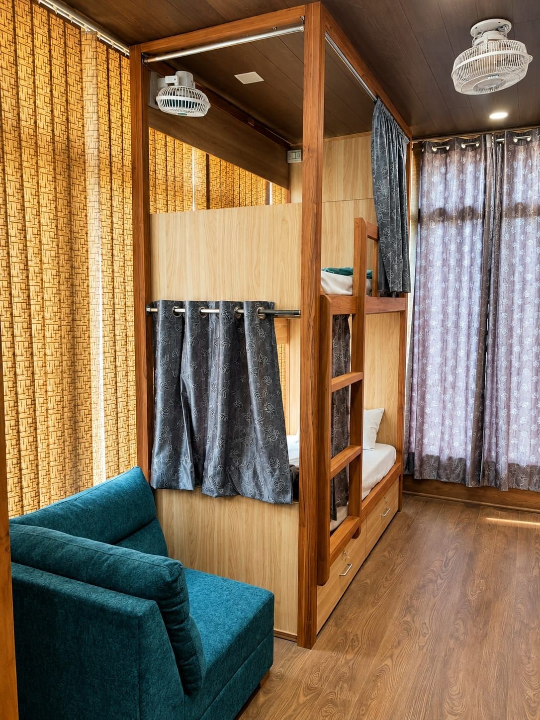 A room with a bunk bed, a sofa, and a ceiling fan.