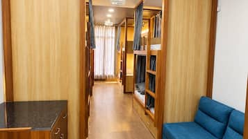 A narrow hallway with wooden walls, a blue sofa, and a kitchenette area.