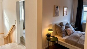 Un dormitorio con cama, mesita de noche, lámpara y decoración en la pared.