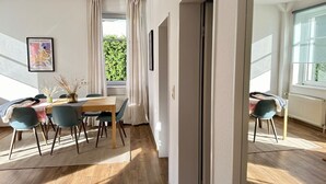 Una sala moderna con comedor, ventanas amplias y vista a la vegetación.