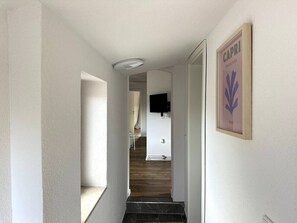 Ein Flur mit Deckenleuchte, einem gerahmten Bild an der Wand und einer Treppe zu einem anderen Raum.