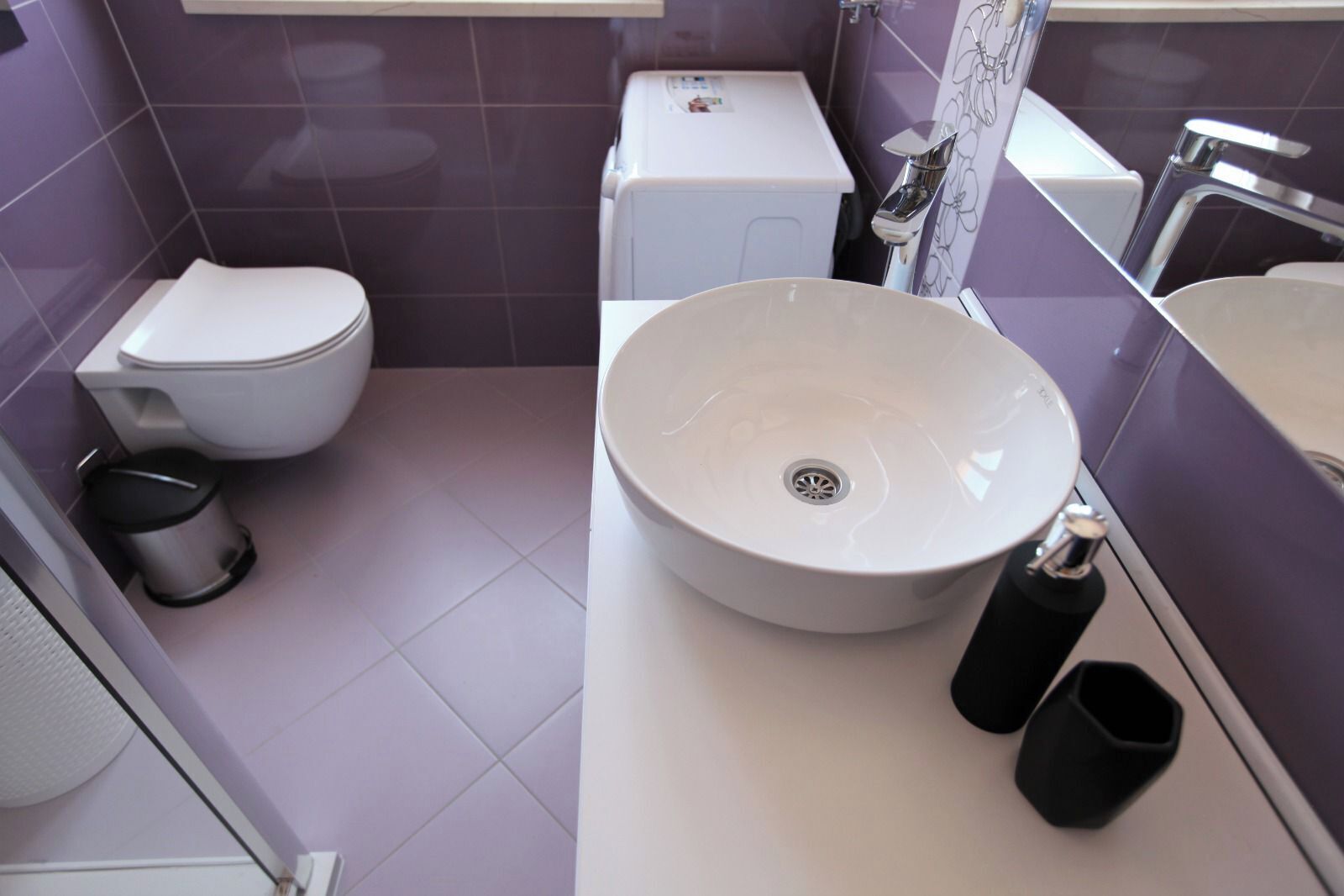 Ein Badezimmer mit Toilette, runder Waschtisch und Mülleimer.
