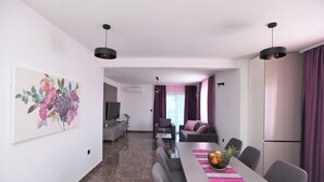 A modern living room with a dining area, a TV, and a plant. - Stunning Seaside Villa PIA First Floor (Okrug Gornji)
