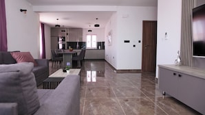 A modern living room with a sofa, a coffee table, and a TV on a cabinet. - Stunning Seaside Villa PIA First Floor (Okrug Gornji)