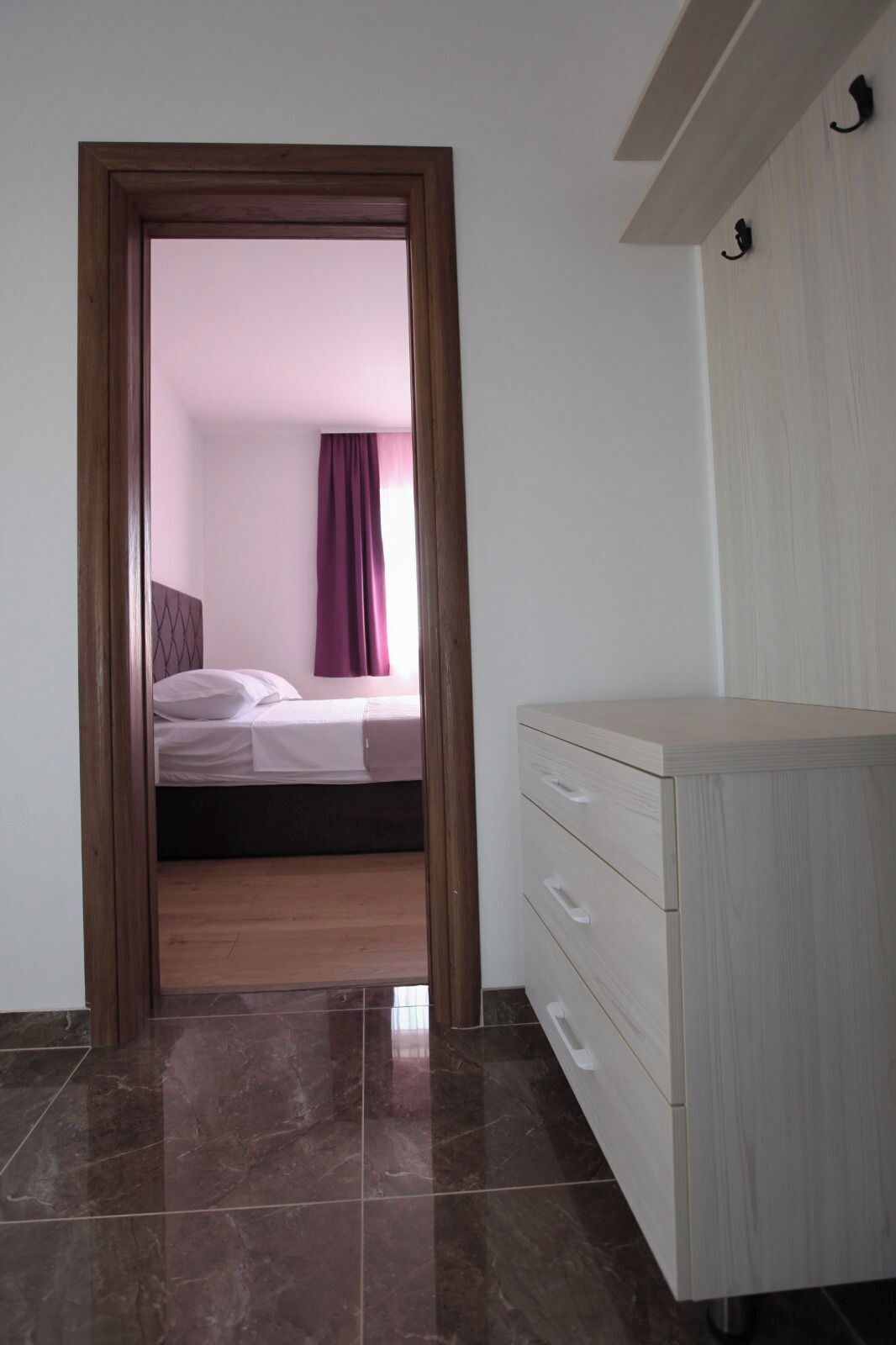 Ein Zimmer mit einem Bett, einem Holzschrank und einem Fliesenboden.