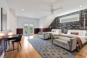 A modern bedroom with a bed, two chairs, a desk, and a ceiling fan. - Monroe Houses (Nashville)
