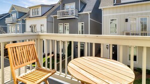 Une terrasse en bois avec une table et des chaises, d’où l’on a vue sur une rangée de maisons de ville dotées de balcons et de fenêtres.