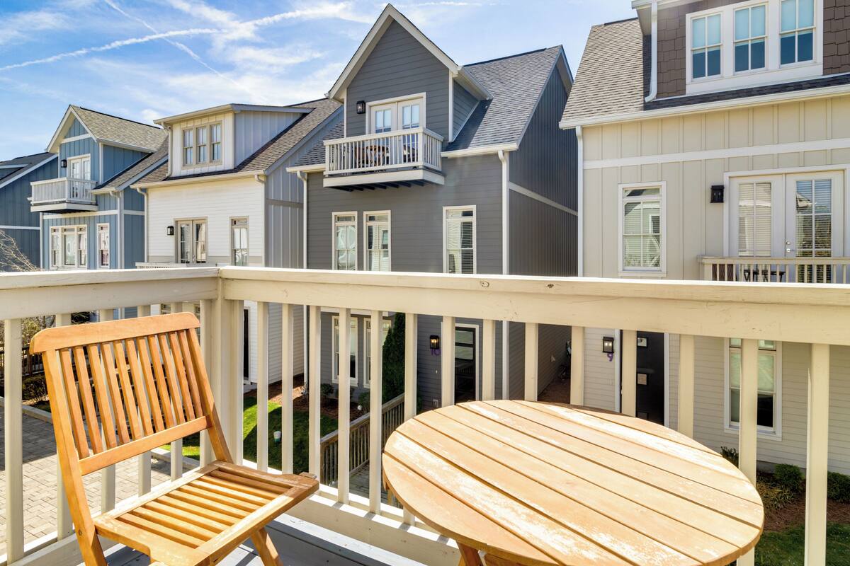 A wooden deck with a table and chairs, overlooking a row of townhouses with balconies and windows.