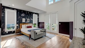 Un dormitorio con cama, mesita de noche, un ventanal y vistas al exterior.