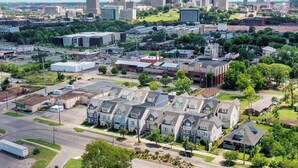 A residential area with modern houses, a commercial zone, and a city skyline in the background. - Monroe Houses (Nashville)