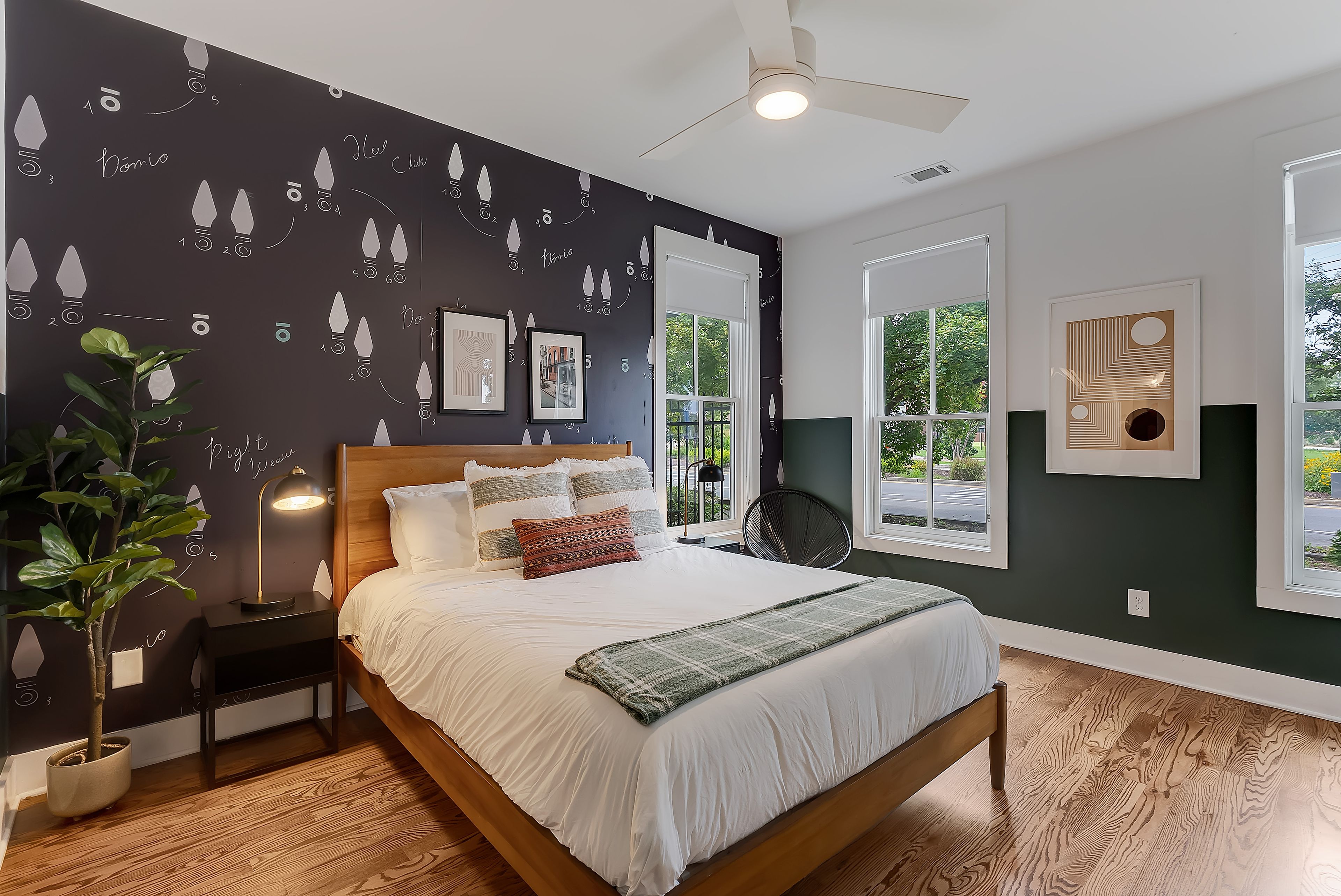 A bedroom with a bed, bedside tables, a nightstand, a potted plant, and a ceiling fan.