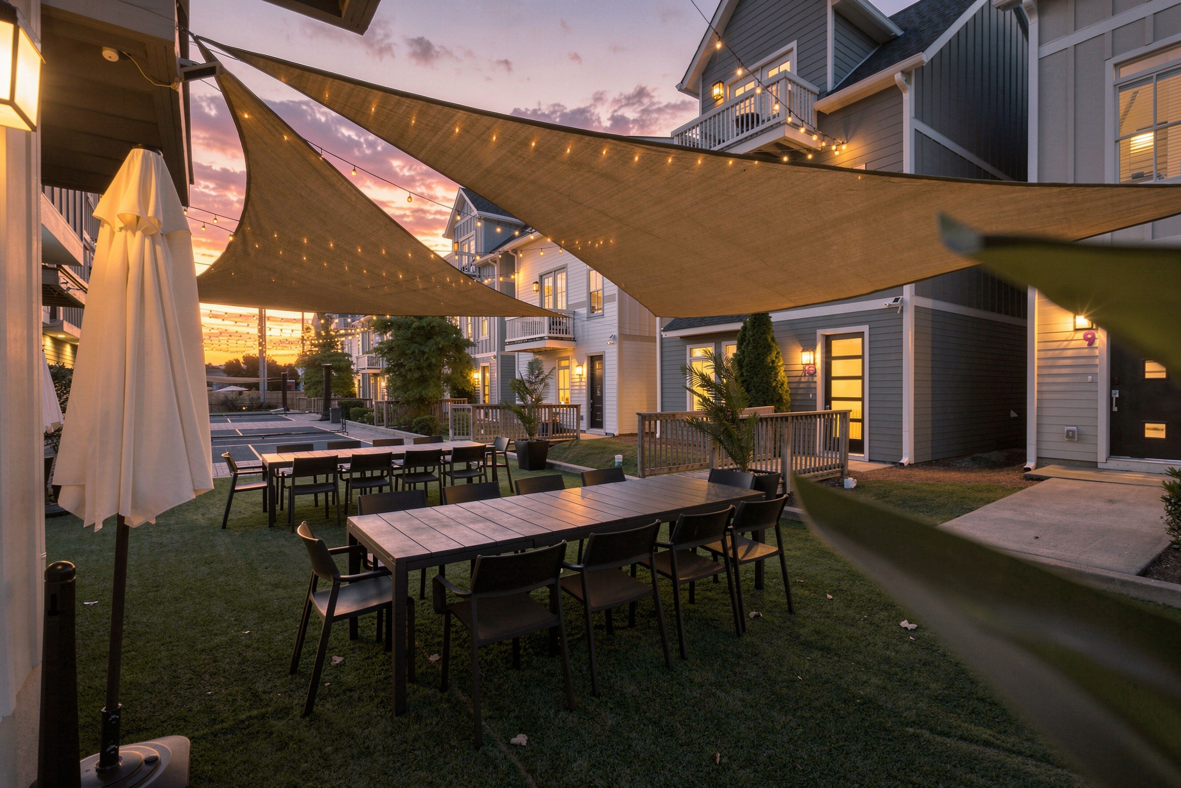 A patio area with tables and chairs, a canopy, and a view of a residential building.