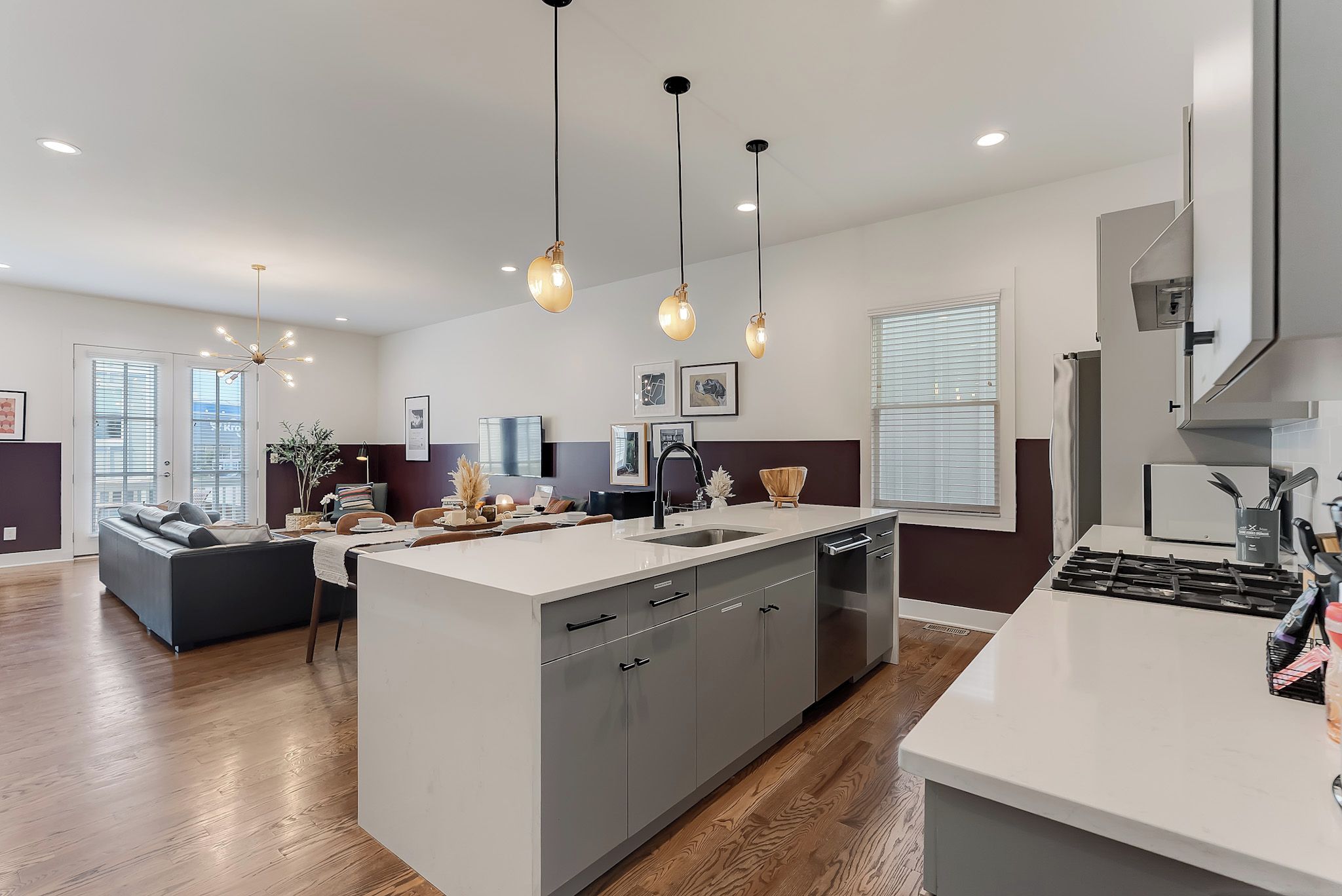 Een moderne keuken met een centraal eiland, grijze kastjes en hanglampen.