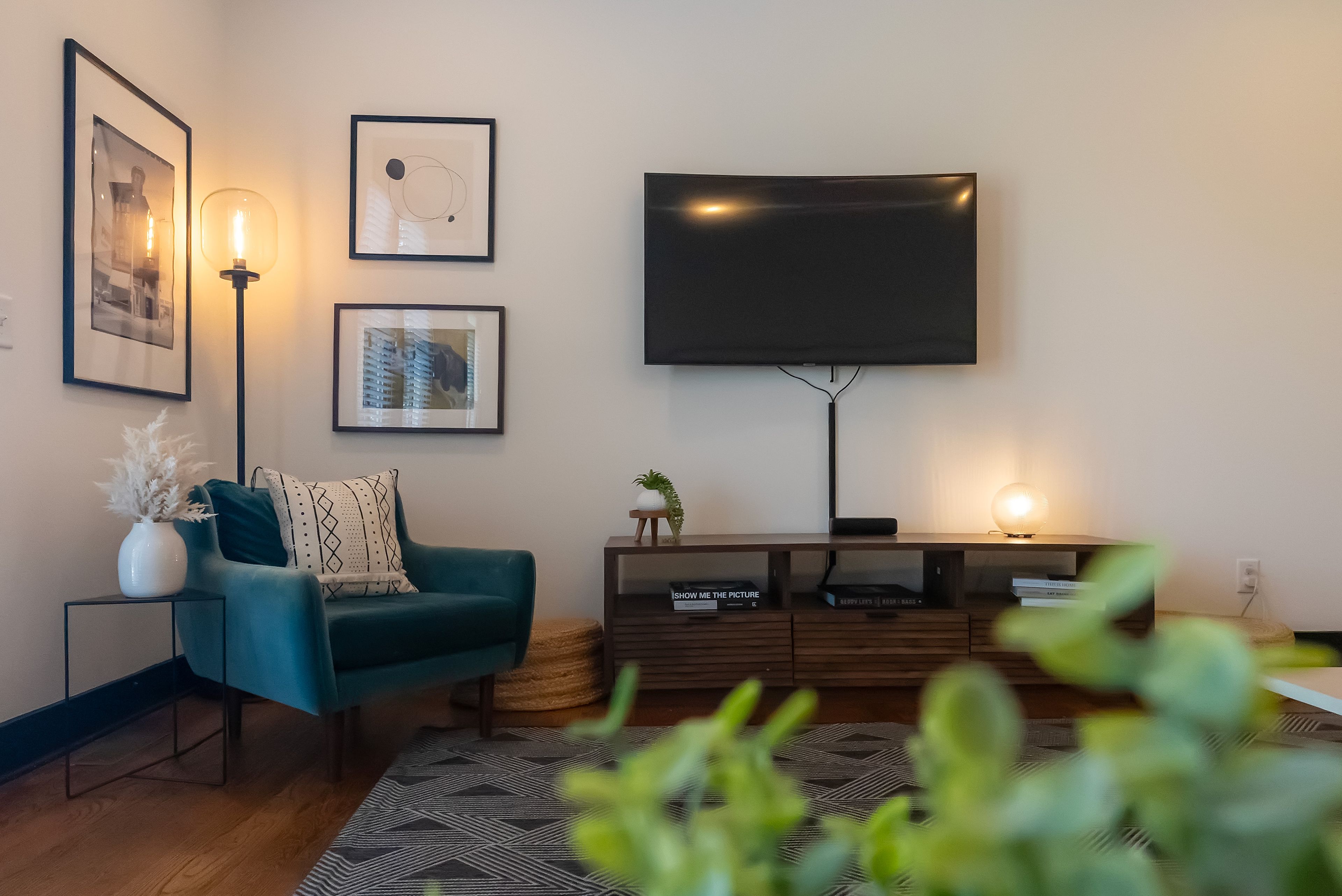 Una sala de estar moderna con un sofá color turquesa, un televisor de pantalla plana y obras de arte enmarcadas en la pared.