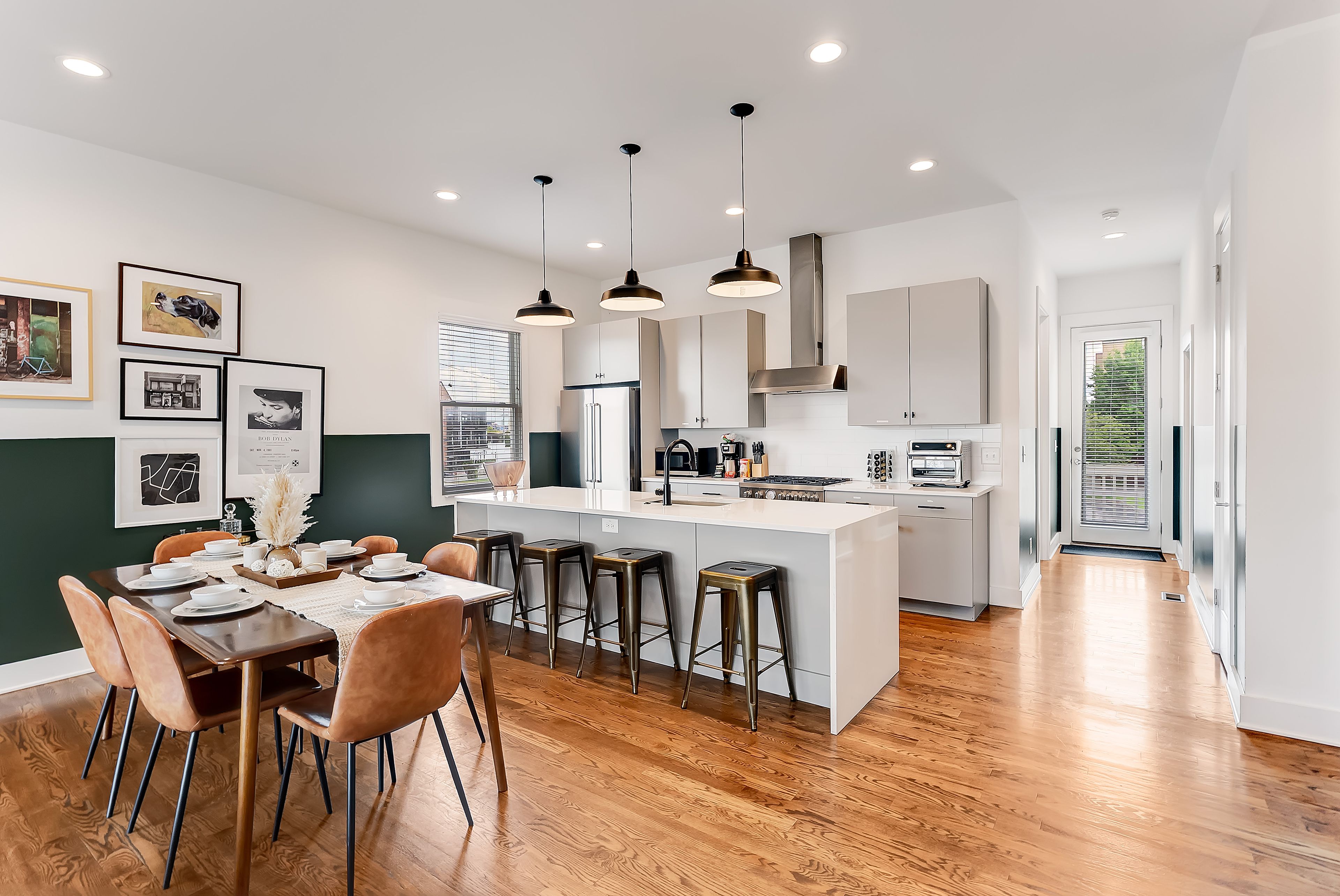 A modern kitchen with a central island, bar stools, and pendant lighting.