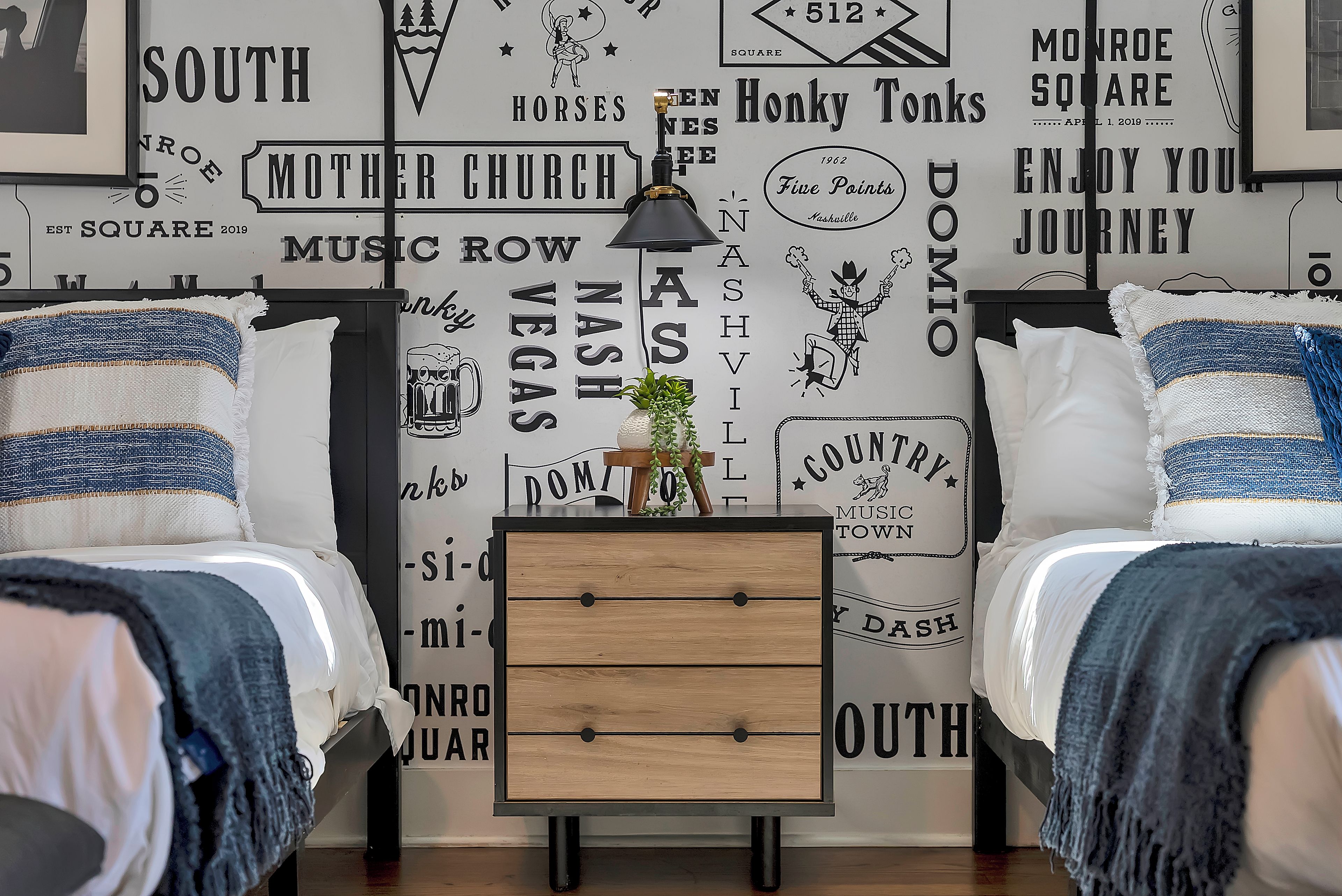 A bedroom with two beds, a nightstand, and a wall with various text and graphics.