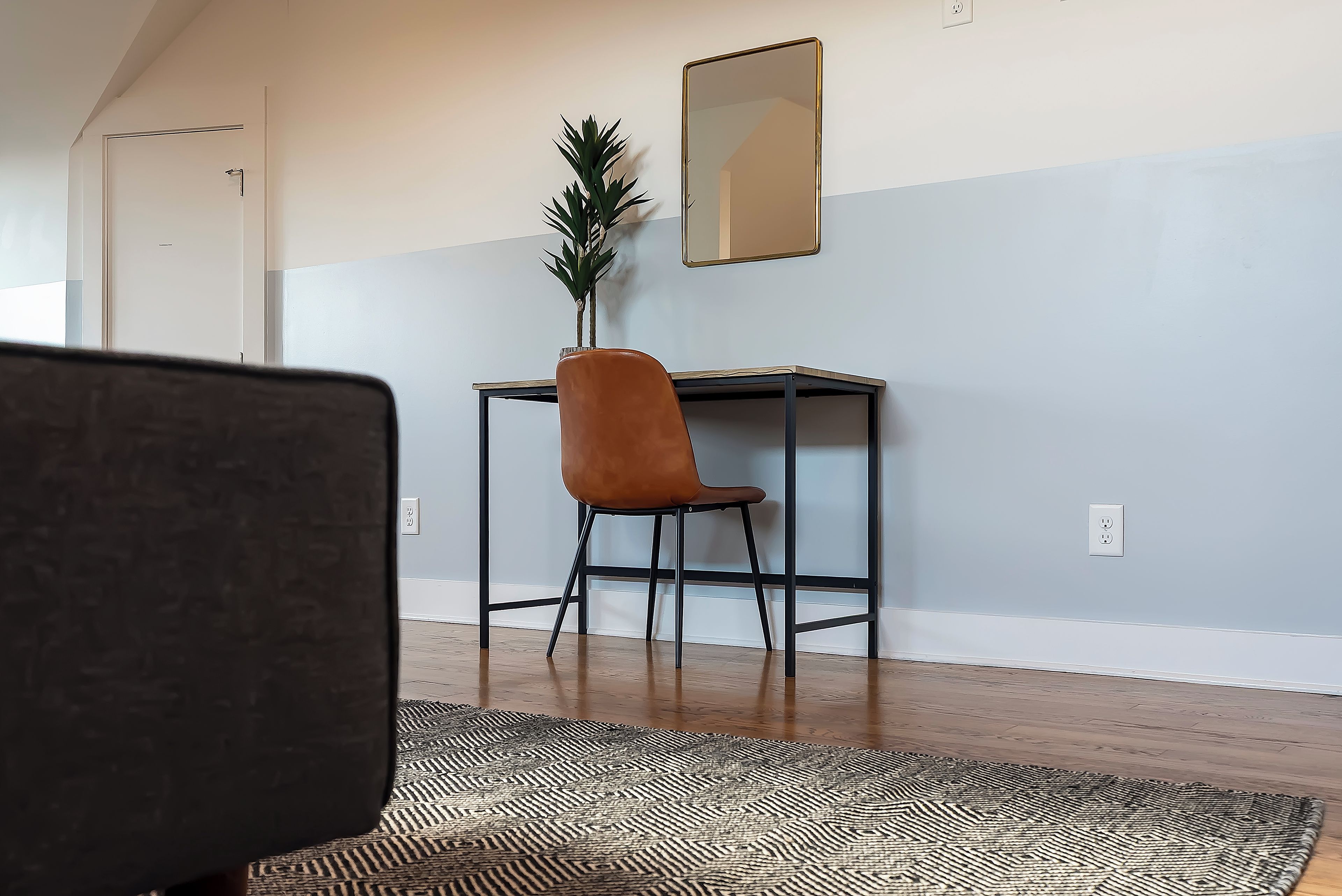 A room with a desk, chair, and a mirror on the wall.