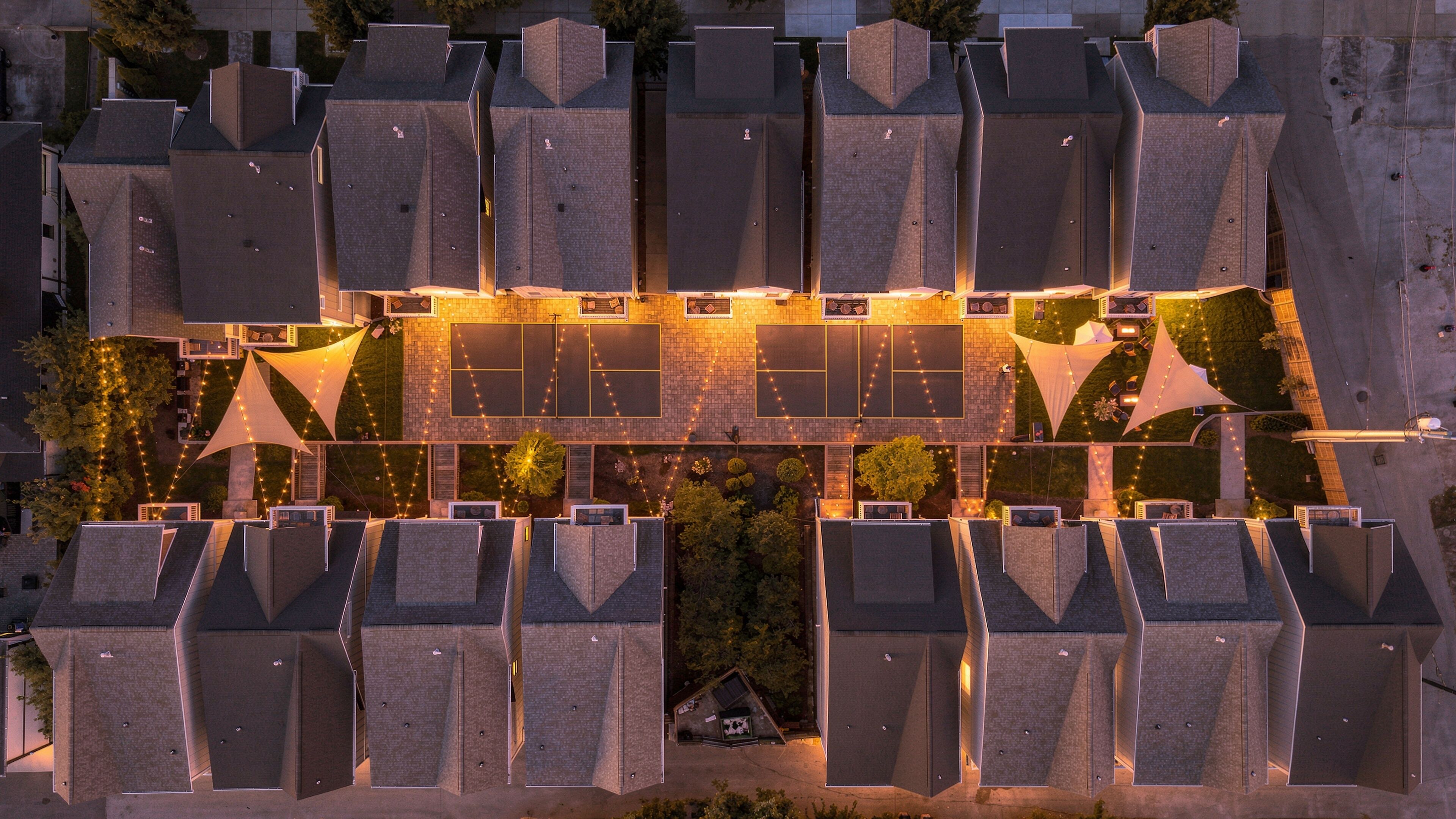 A modern building with multiple rooftop terraces, some with seating areas and others with greenery.