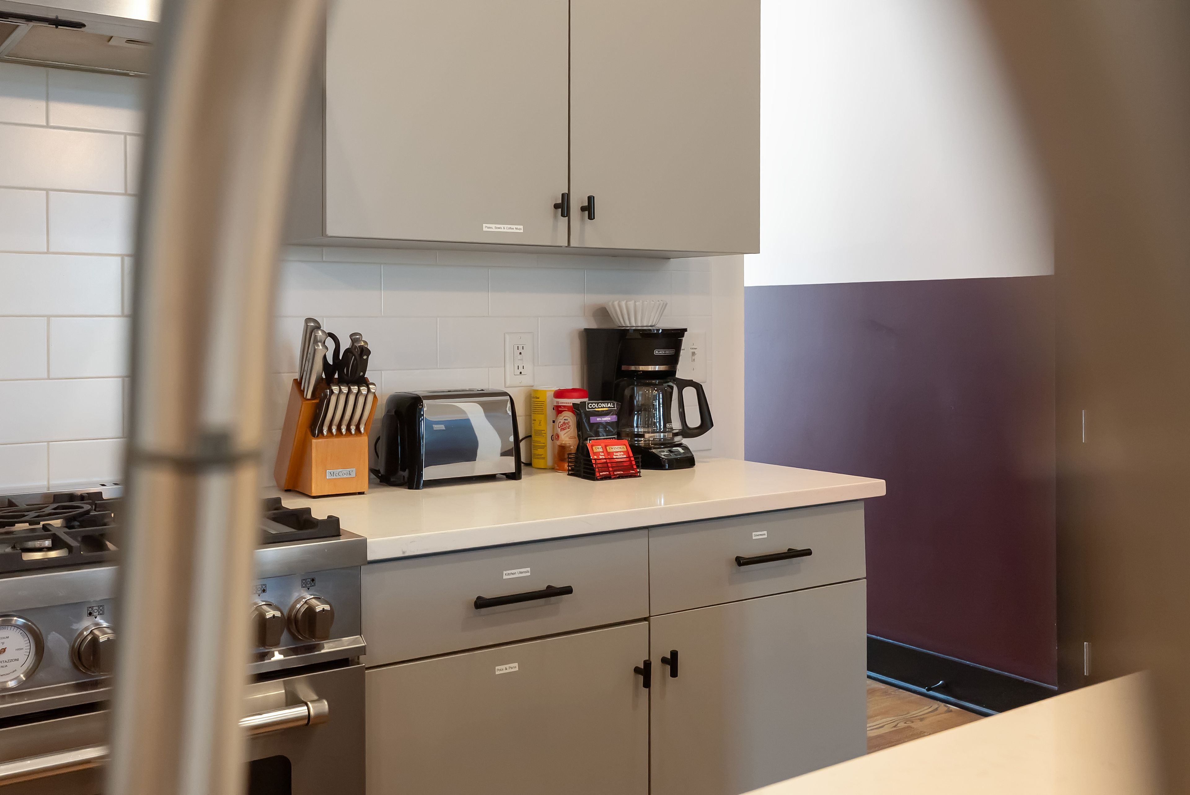 Une cuisine équipée d’une cuisinière à gaz, d’une machine à café et d’un grille-pain posés sur le plan de travail.
