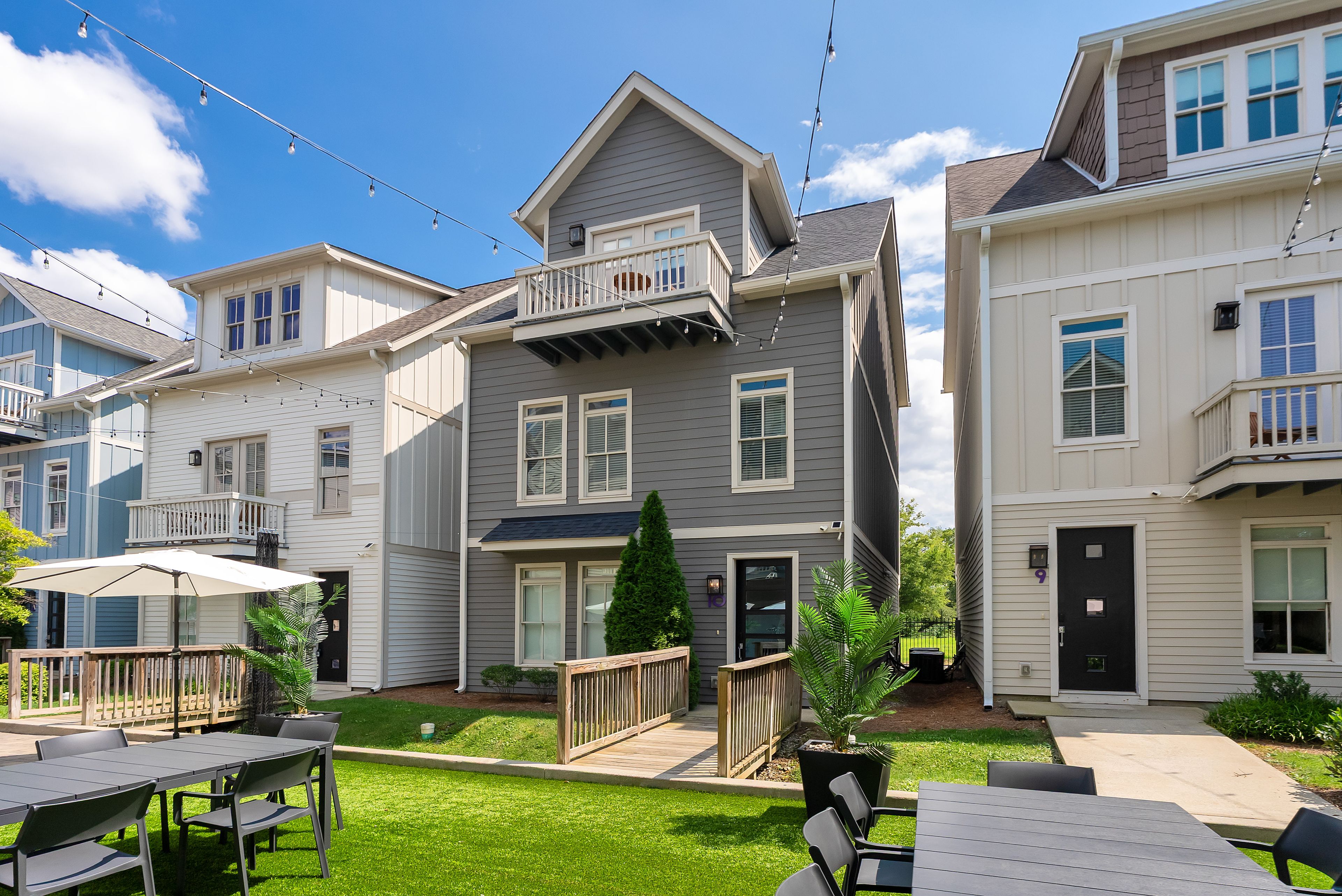 A residential building with a balcony, a front door, and a small garden area with outdoor furniture.