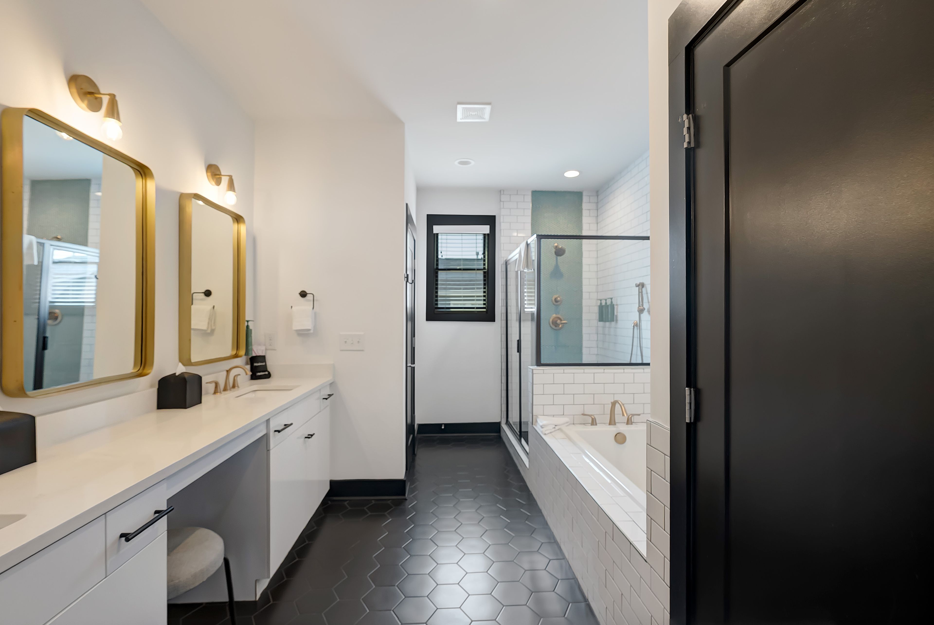 A modern bathroom with a white vanity, a glass shower enclosure, and a black door.