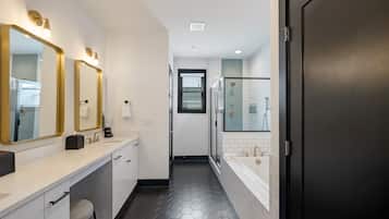 A modern bathroom with a white vanity, a glass shower enclosure, and a black door.