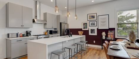 Una cocina moderna con una isla central, electrodomésticos de acero inoxidable e iluminación colgante.