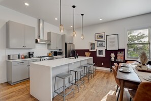 Una cocina moderna con una isla central, electrodomésticos de acero inoxidable e iluminación colgante.