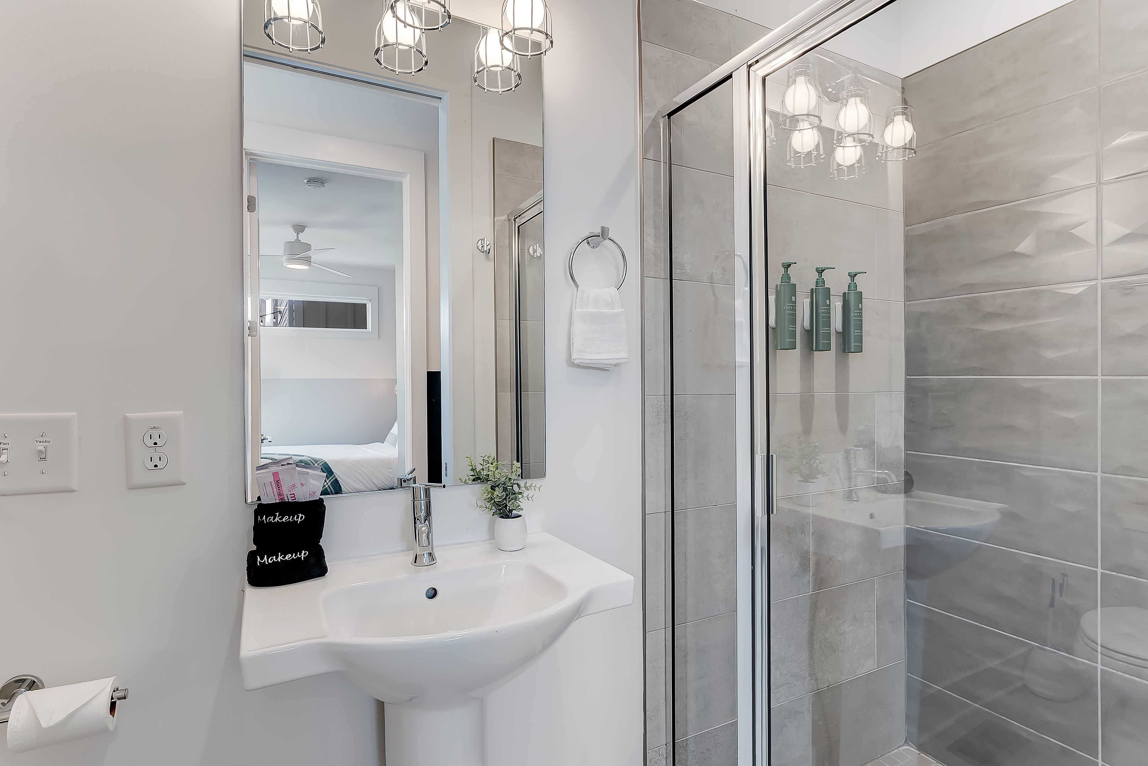 A modern bathroom with a glass shower enclosure, a white sink, and a vanity mirror.