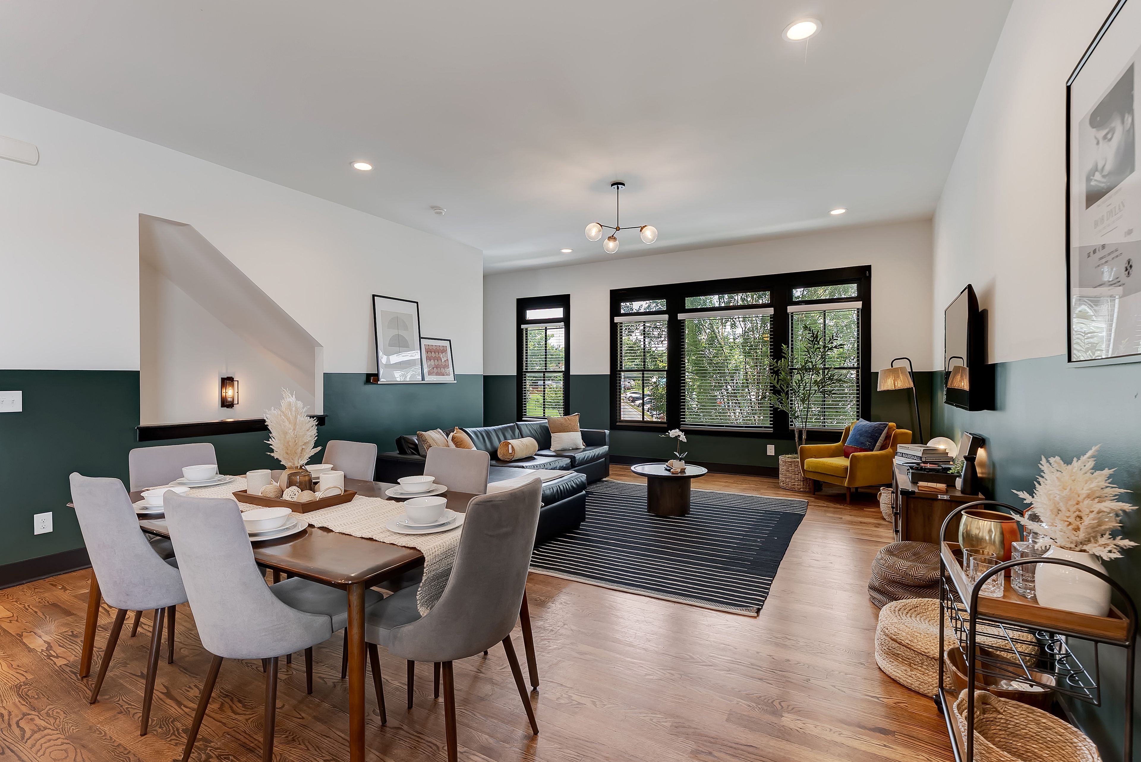 Un salon moderne avec un coin repas, comprenant un canapé, des fauteuils, une table basse et une table à manger pour quatre personnes.