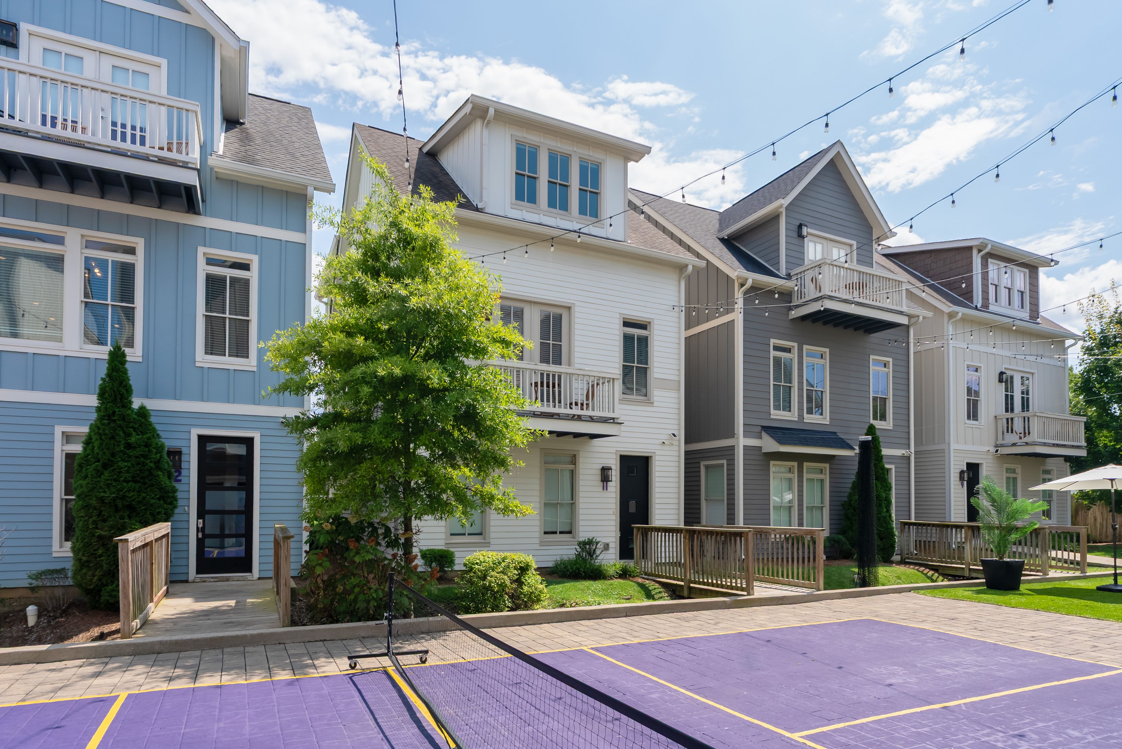 A residential area with multi-story houses, a basketball court, and a well-maintained lawn.