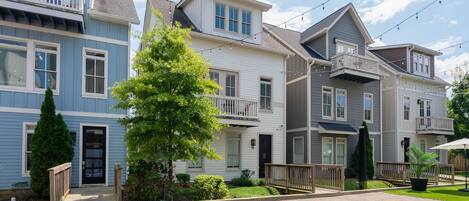 A residential area with multi-story houses, a basketball court, and a well-maintained lawn.