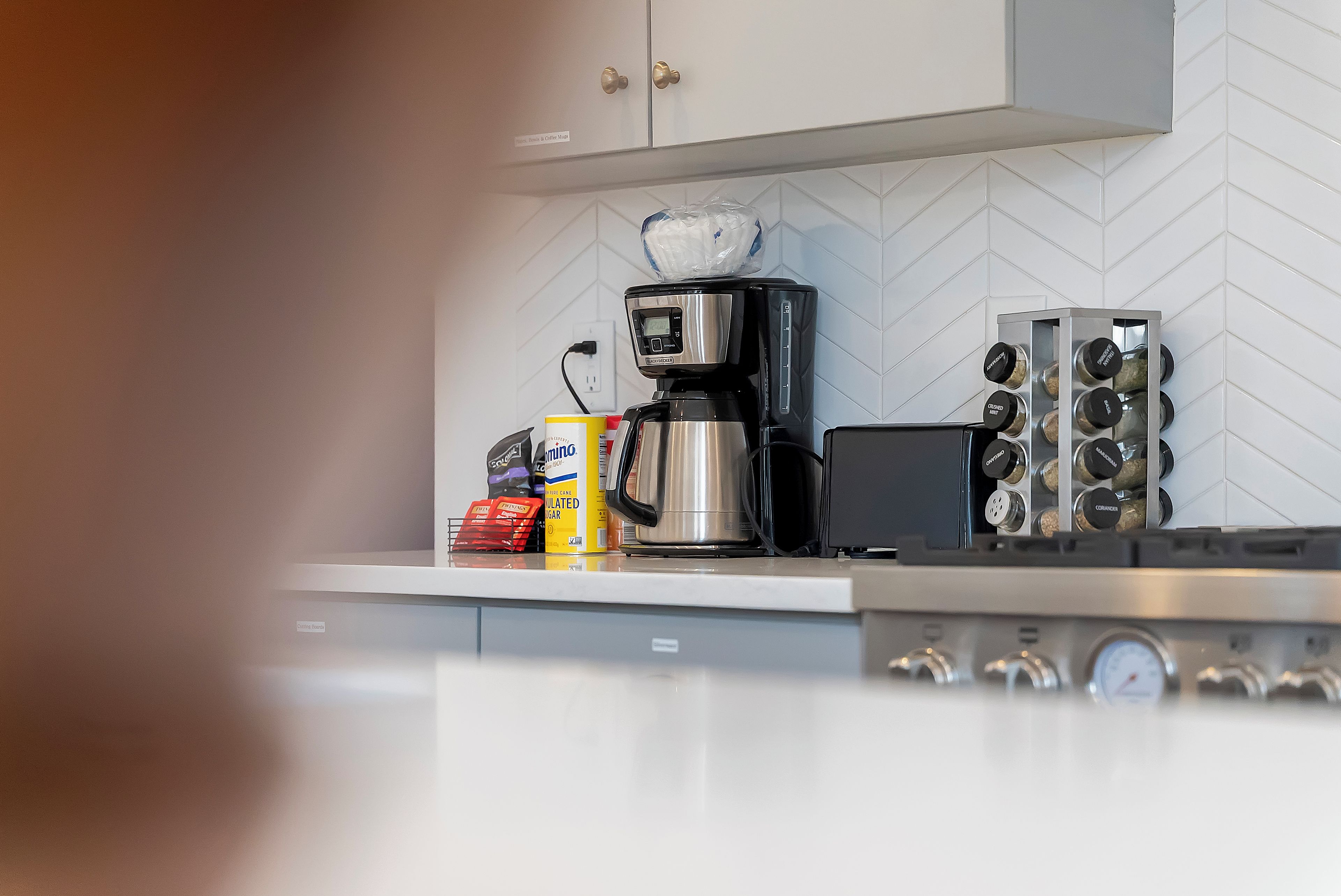 Een keuken met een koffiezetapparaat, een broodrooster en een kruidenrek.