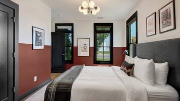 A hotel room with a bed, a window with a view, a door, and a ceiling light fixture.