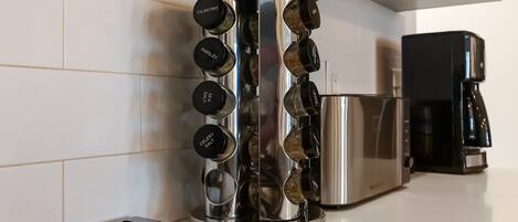 A kitchen with a stainless steel spice rack holding various spices and a coffee maker on the counter.
