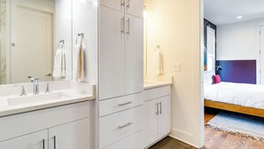 Une salle de bain moderne avec un grand miroir, deux vasques et une douche à l’italienne.
