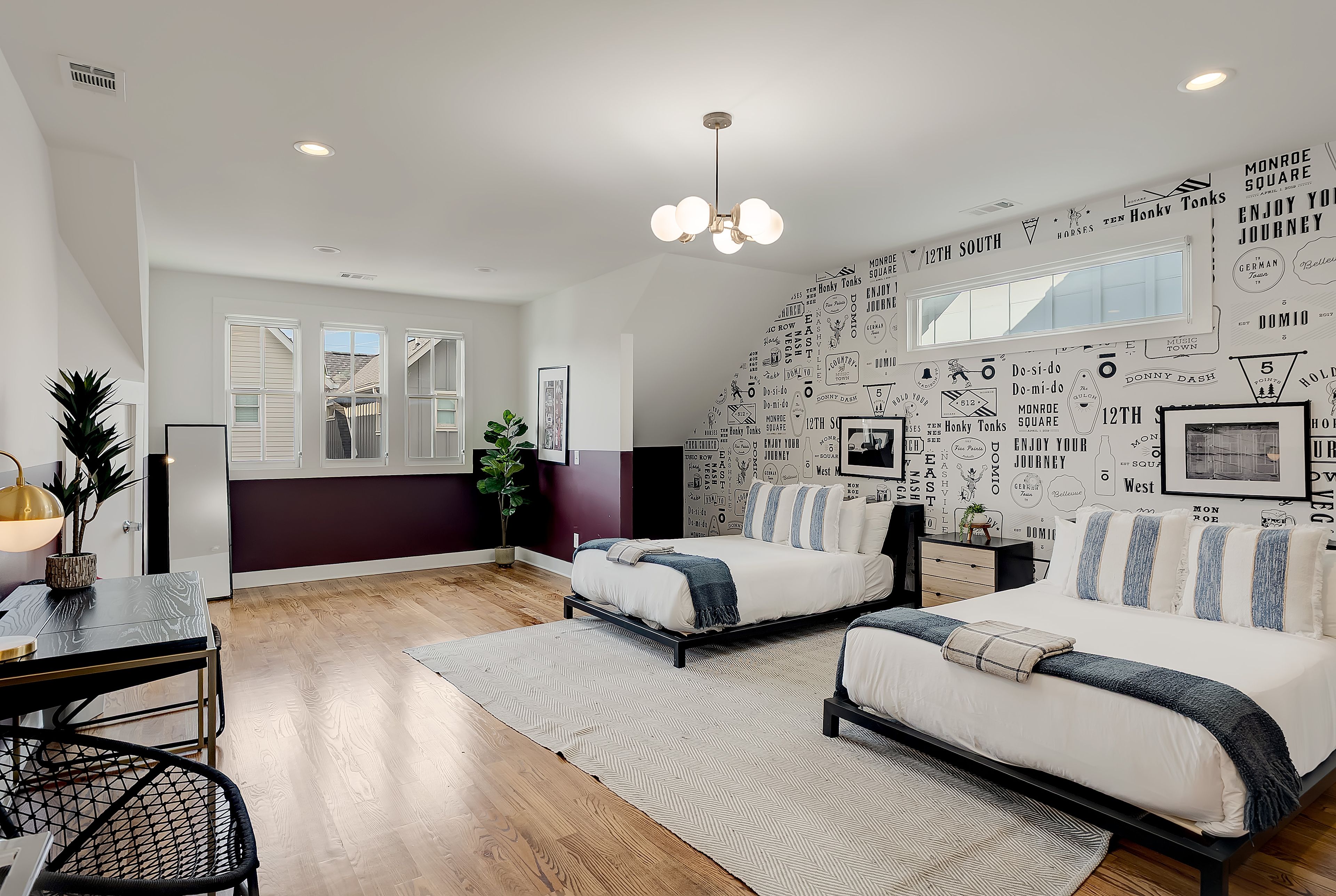 A bedroom with two beds, a dining area, and a wall with various text and images.