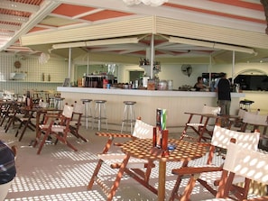 Un restaurante con terraza, bar y mostrador con diversos productos.