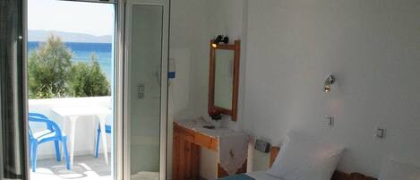 Una habitación con dos camas, un escritorio, un espejo y vistas al mar.