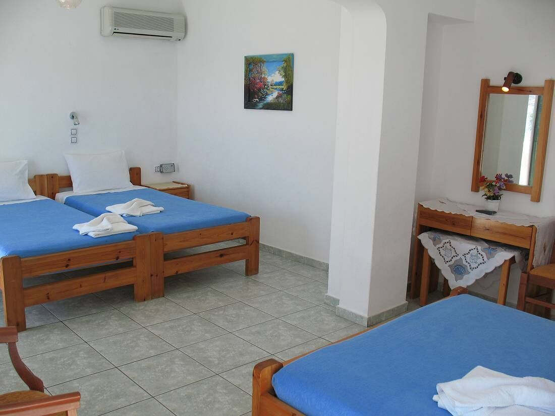 A room with two wooden beds, a small desk with a mirror, and a painting on the wall.