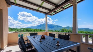 A covered outdoor seating area with a table and chairs, a view of mountains, and a clear sky. - Perfect 3-bedroom house with heated pool in peaceful Šestanovac (Šestanovac)