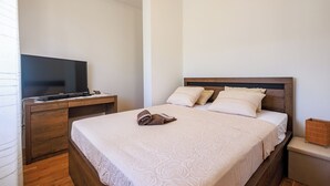 A neatly made bed with a patterned bedspread, a television on a wooden stand, and a wooden nightstand with a small decorative item. - Perfect 3-bedroom house with heated pool in peaceful Šestanovac (Šestanovac)