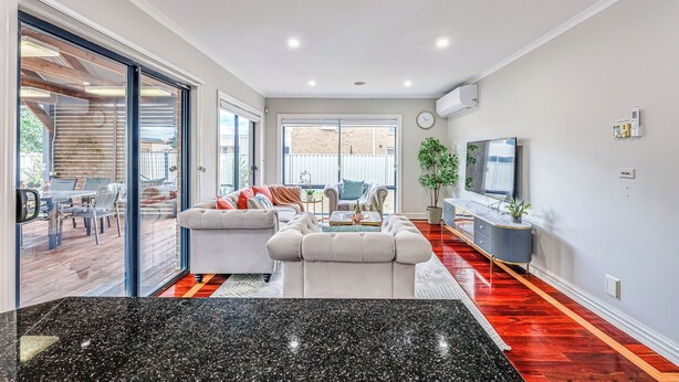 A modern living room with a sofa, TV, and a dining area with chairs and a table. - StayAU PoolTable 2-Story Pet-friendly  (Caroline Springs)