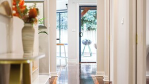 A hallway with a polished wooden floor, white walls, and a door leading outside. - StayAU PoolTable 2-Story Pet-friendly  (Caroline Springs)