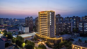 A high-rise hotel with multiple floors, a prominent entrance, and a well-lit facade. - Hampton by Hilton Tianjin Baodi (Tianjin)