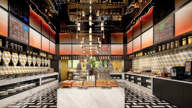 A modern coffee shop interior with a central counter, shelves with coffee beans, and a patterned floor. - Hampton by Hilton Tianjin Baodi (Tianjin)