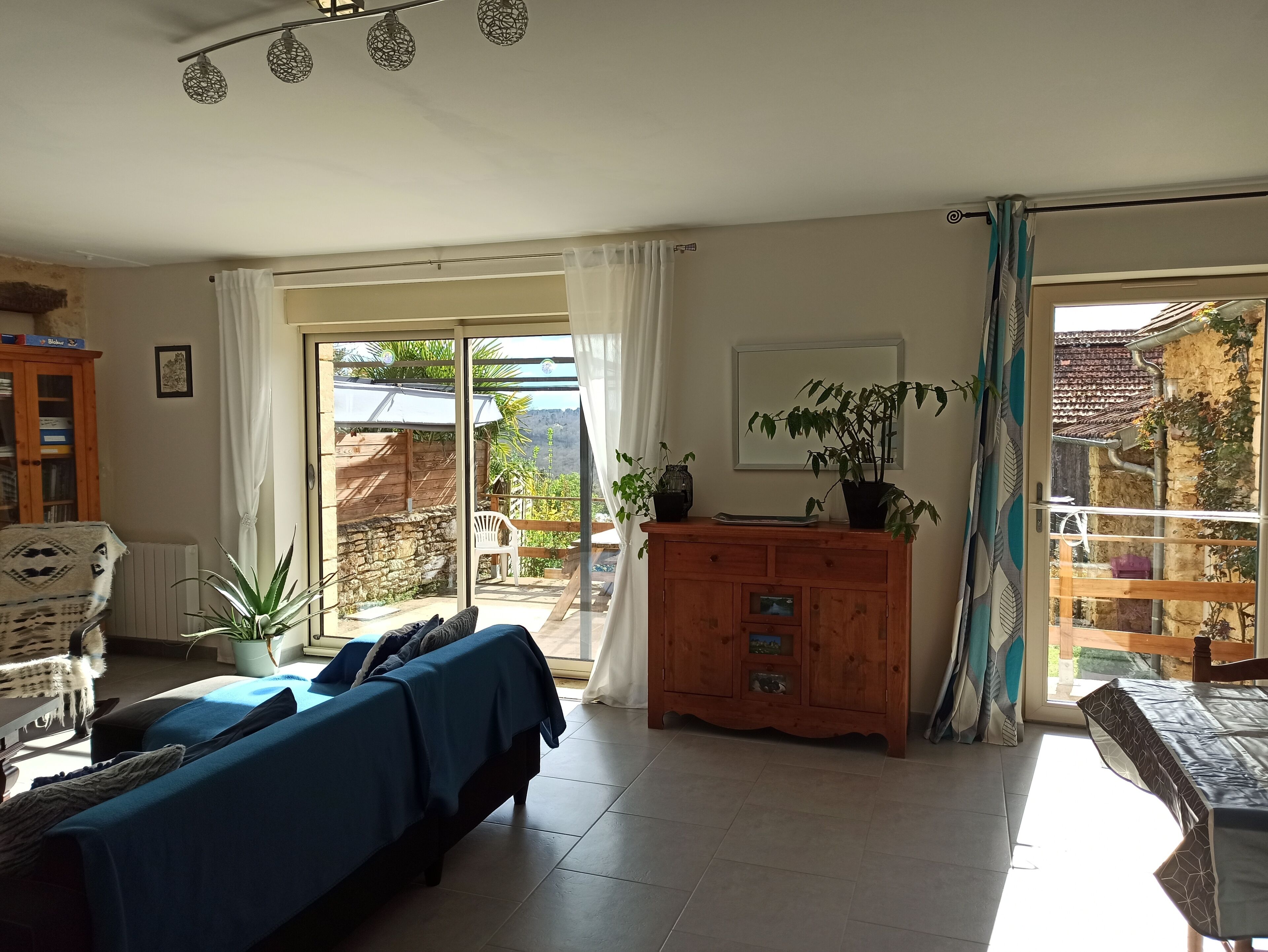 Una habitación con una cama, un armario de madera, una planta en maceta y vistas al exterior.